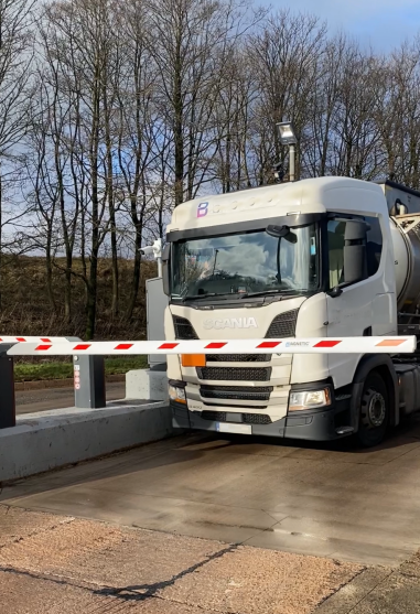 Truck in front of the entrance barrier of the Junction 38 Truckpark, a HUB Parking Technology facility.